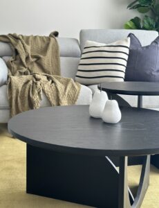 Modern living room setup with round coffee tables, neutral sofa, and decorative cushions.