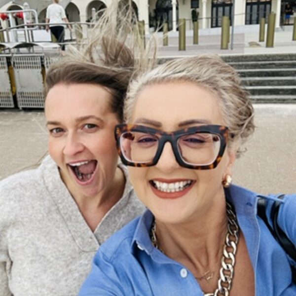 Two smiling women at an outdoor location, showcasing happiness.