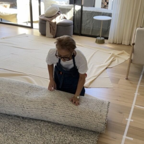 Person arranging a rug in a modern interior design gallery space