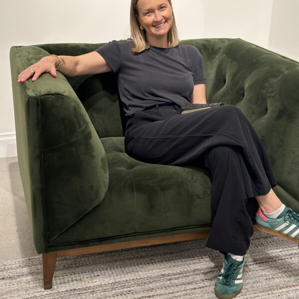 Person sitting on a stylish green sofa in interior design gallery.