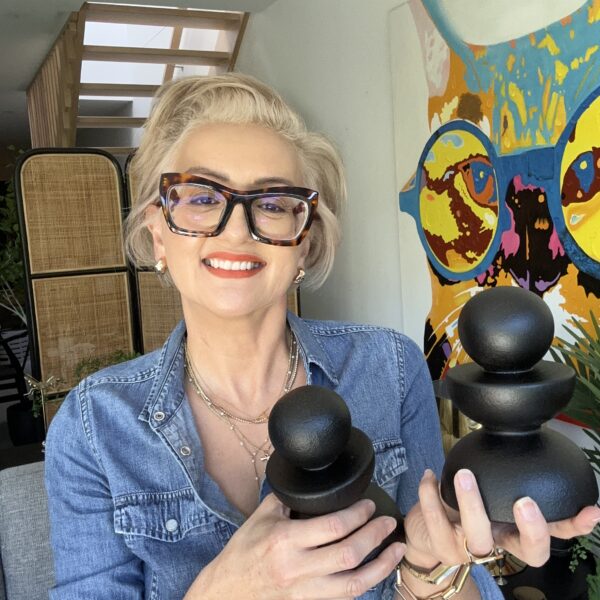 Smiling woman holding sculptures in an interior design gallery