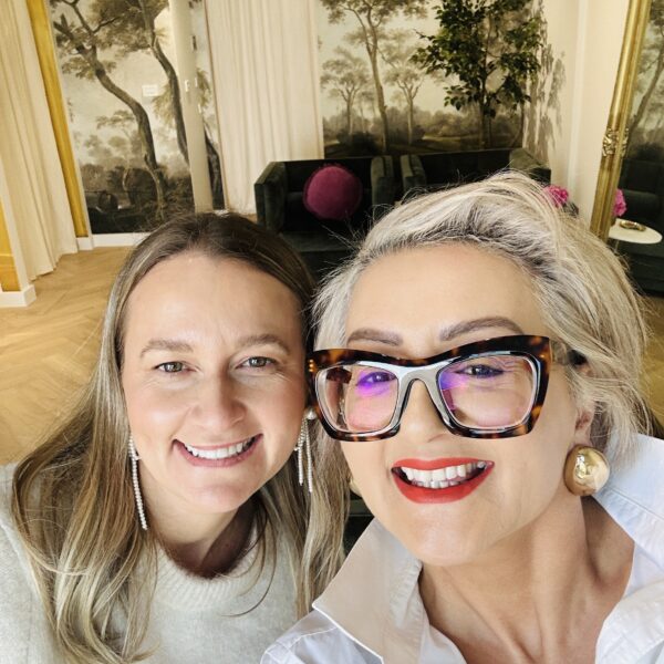 Two smiling women in an interior design gallery setting.