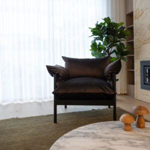 Elegant lounge with plush chair and leafy plant in beachside townhouse.