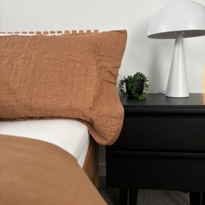 Modern bedroom in Beachside Townhouse Gallery with brown pillow, black nightstand and white lamp.