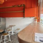 Interior of Gelato Lab Gallery with orange walls and white stools